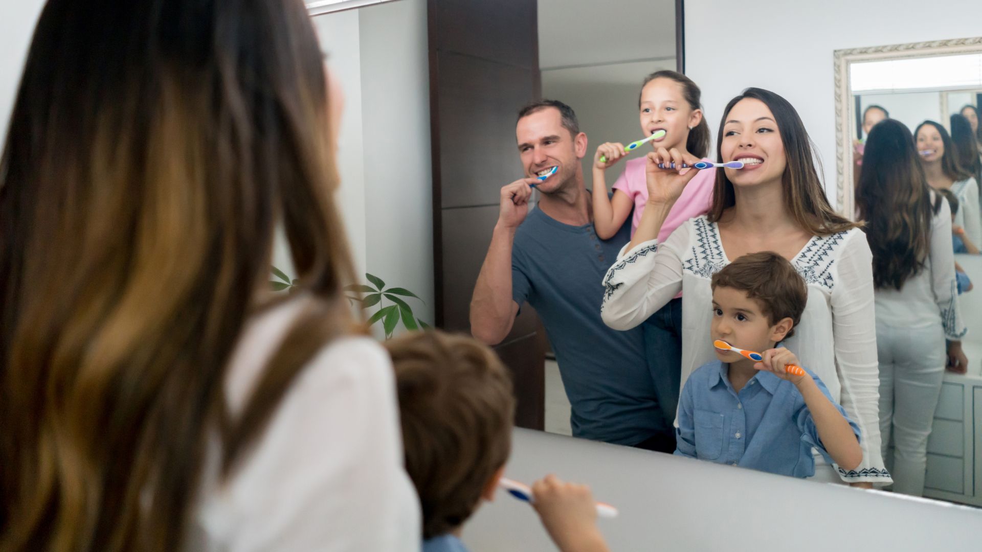 Family brushing teeth in bathroom mirror.