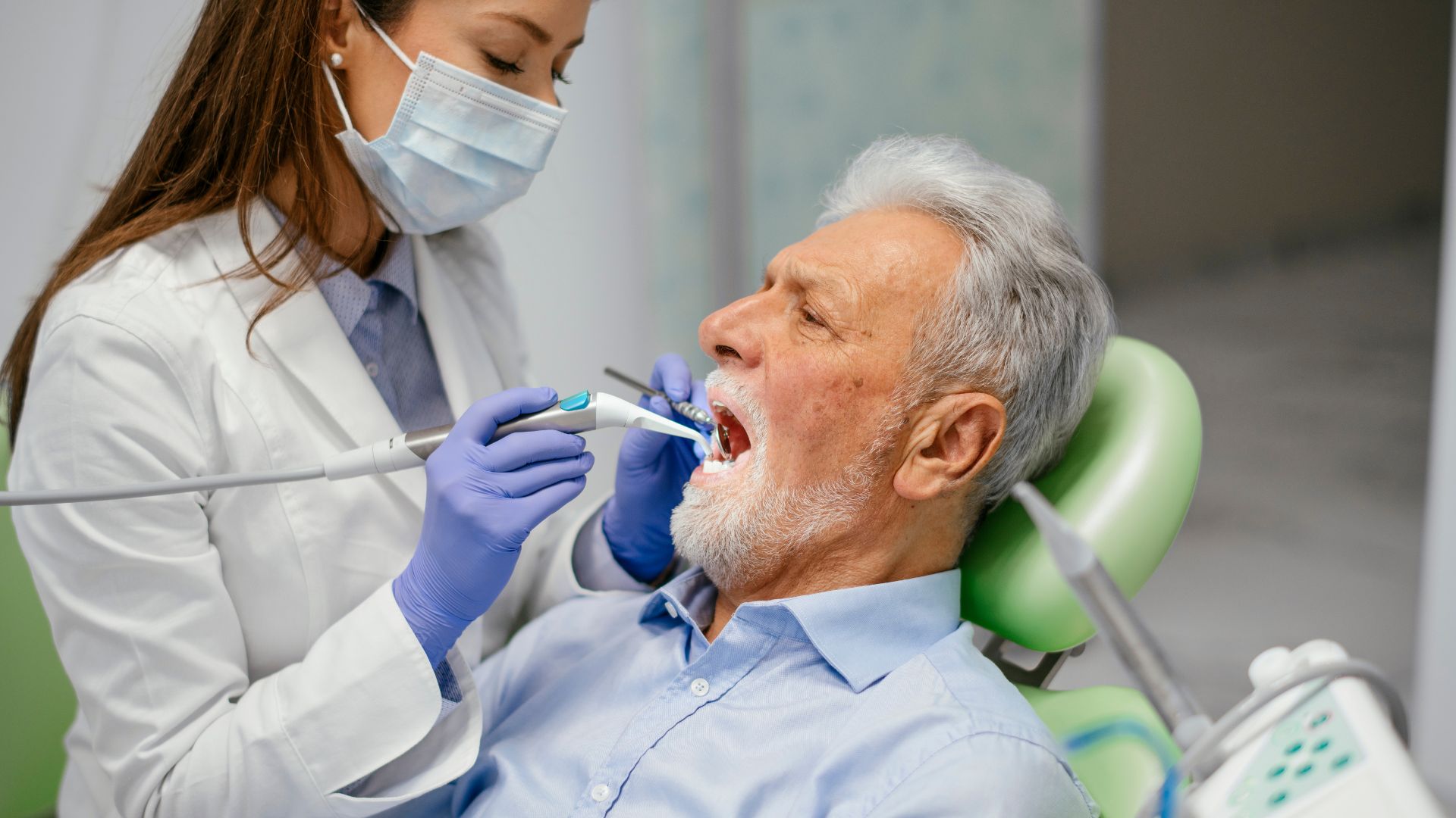 Dentist examining an elderly man's teeth.
