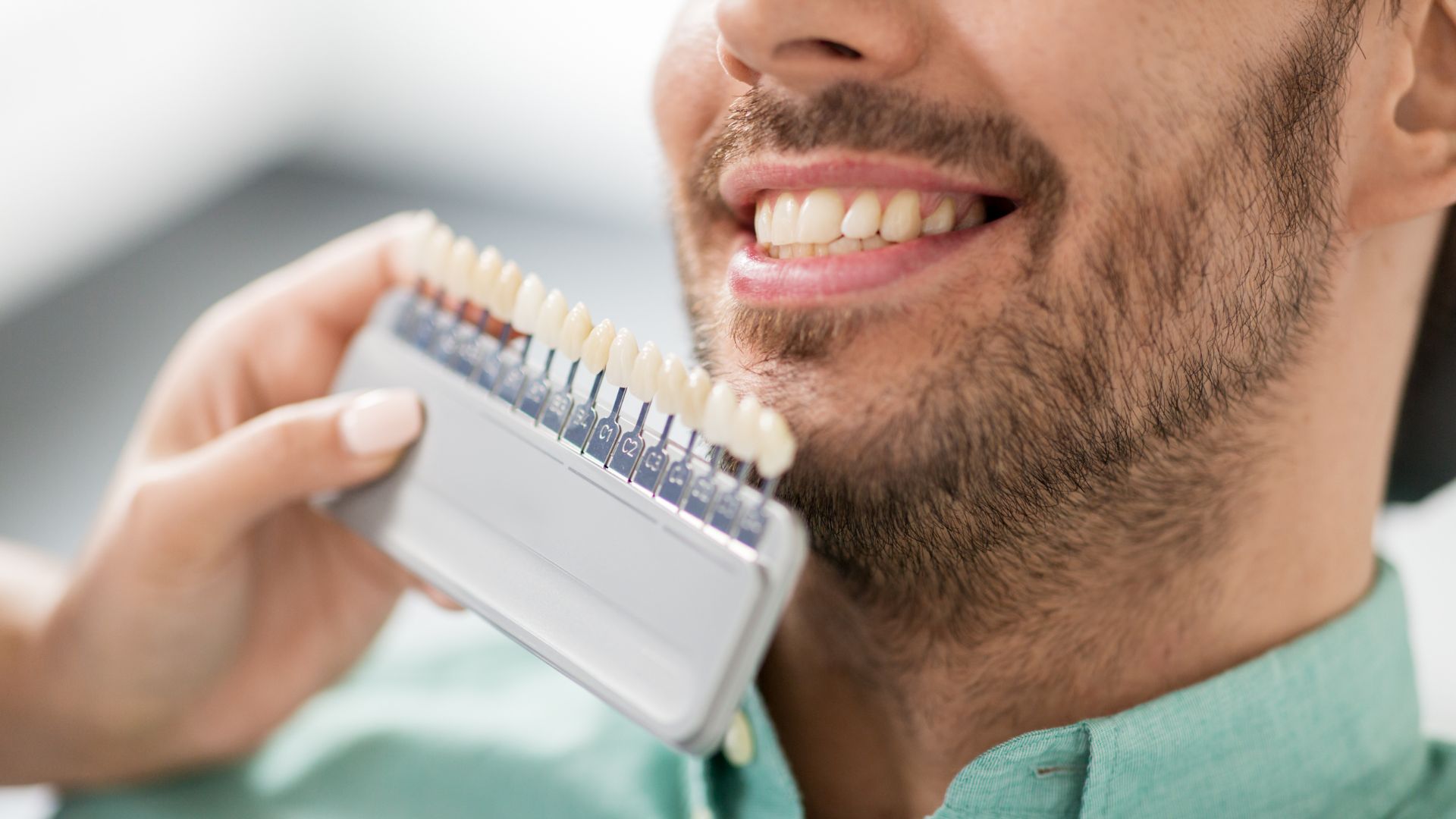 Man matching tooth color with shade guide.