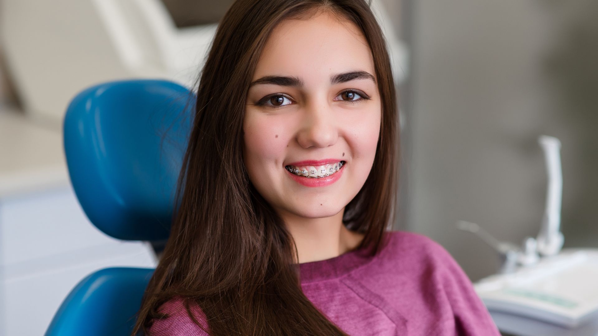 Smiling girl with braces at dentist.