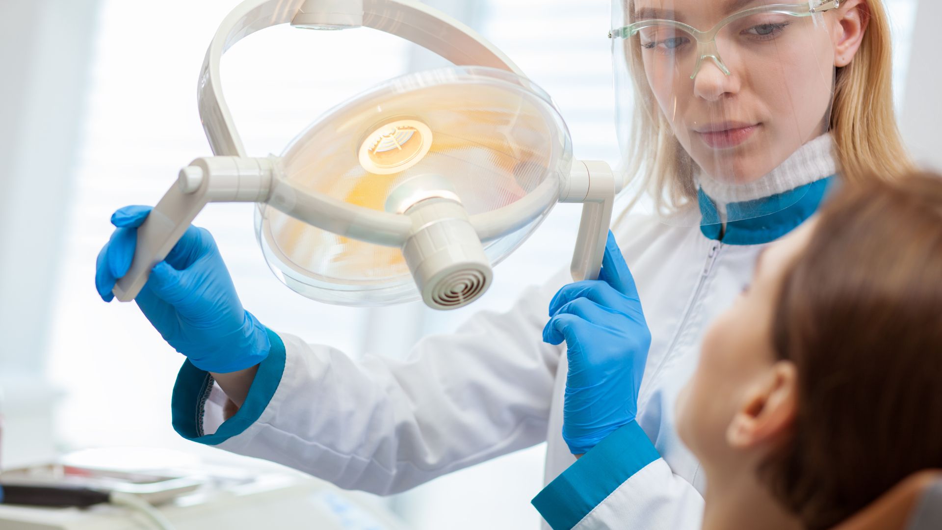 Dentist adjusting light above patient.