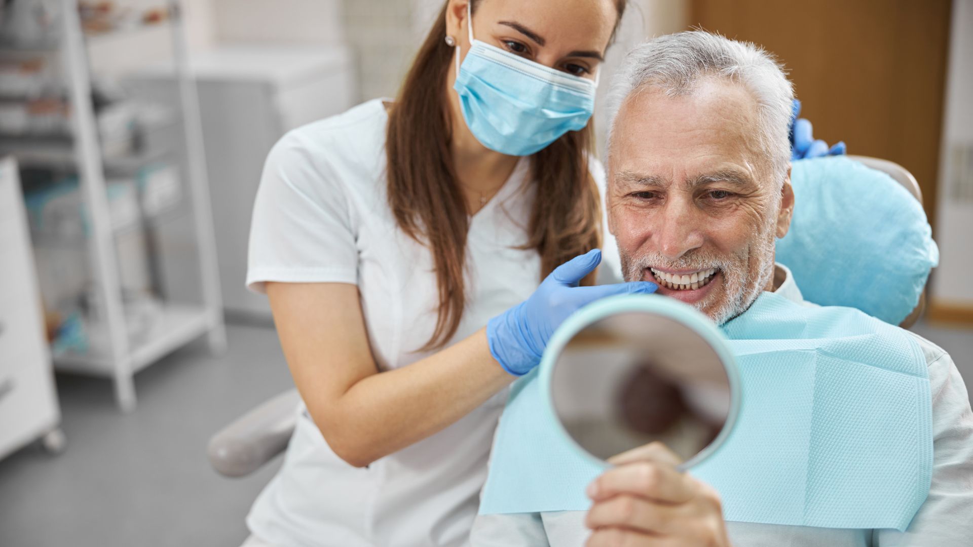 Dentist and patient smiling with mirror.