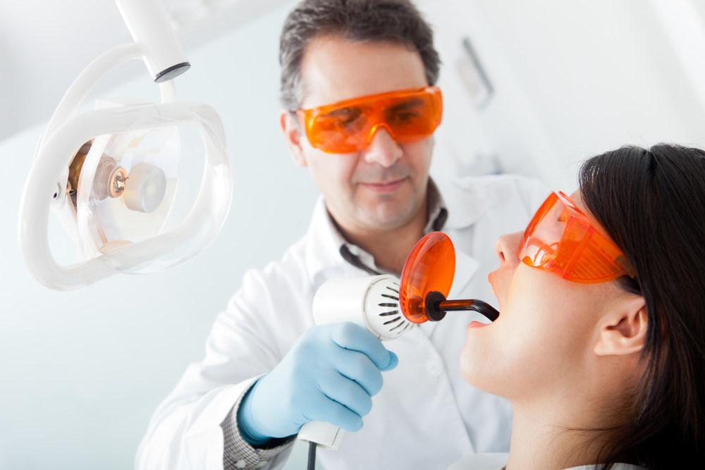 Dentist performing procedure with protective eyewear.